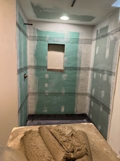 A bathroom is being remodeled and a pile of sand is on the floor.