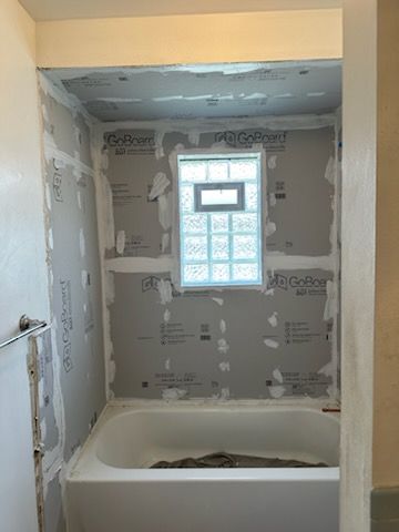 A bathroom with a bathtub and a window.