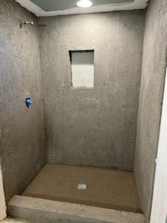 A concrete shower stall with a window in the wall.