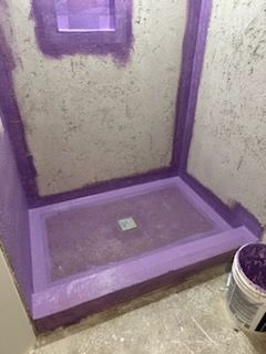 A purple shower stall is being built in a bathroom.