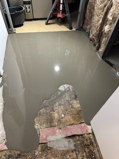 A concrete floor is being poured in a room.