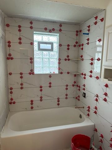 A bathroom with a tub and a window being tiled.