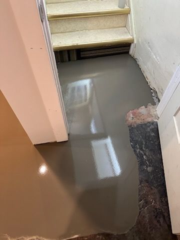 A room with stairs and a concrete floor.