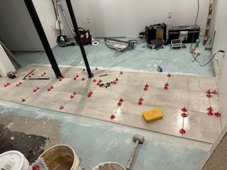 A room with a lot of tiles on the floor and a yellow sponge on the floor.