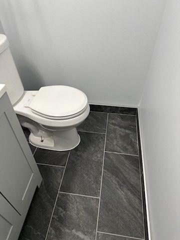 A toilet is sitting on a tiled floor in a bathroom next to a sink.