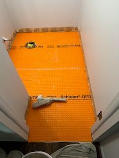 A bathroom floor is being remodeled with an orange mat on it.