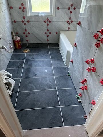 A bathroom with a black tile floor and a bathtub.