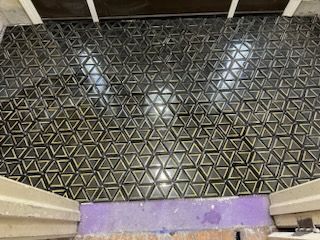 A black tile floor with a geometric pattern is being installed.