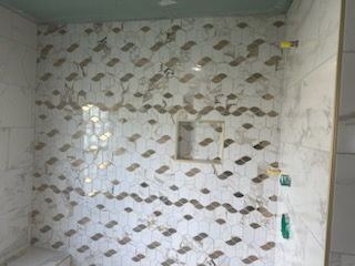 A bathroom with a shower stall and a marble wall.