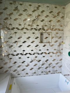 A bathroom with a bathtub and a shower with a marble wall.