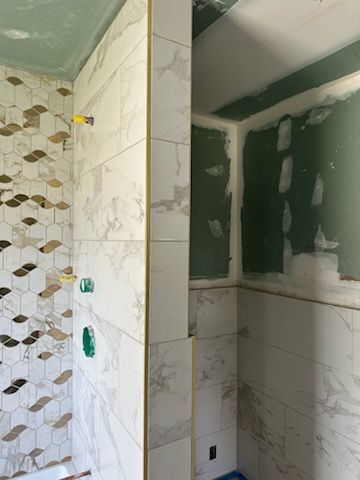A bathroom under construction with marble tiles and a shower stall.