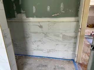 A bathroom under construction with marble tiles on the wall and floor.