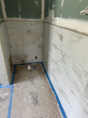 A bathroom under construction with marble tiles and a roll of toilet paper.