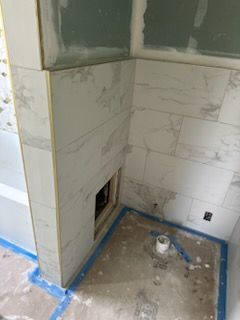 A bathroom under construction with white tiles and a toilet.