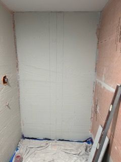 A bathroom with a white wall and a blue tarp on the floor.