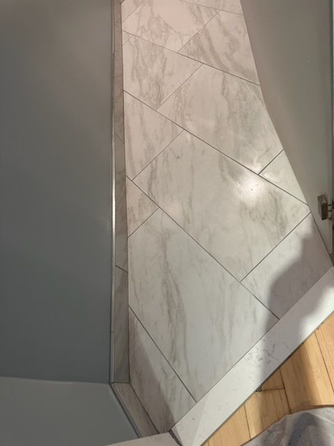 A bathroom with marble tiles and a wooden floor.