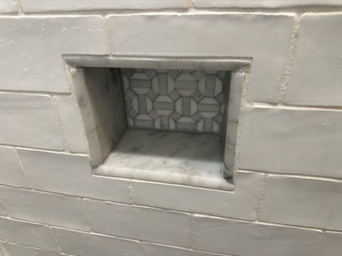 A shower niche in a bathroom with white tiles.