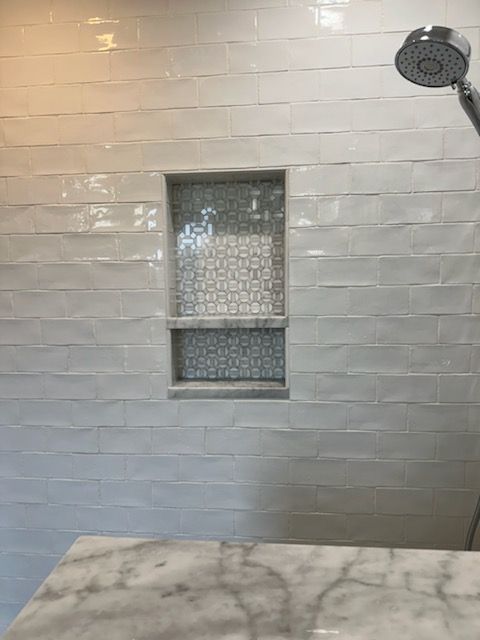 A shower with a built in shelf and a shower head.