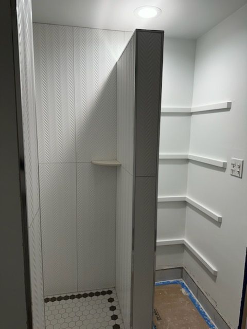 A bathroom with a walk in shower and shelves.