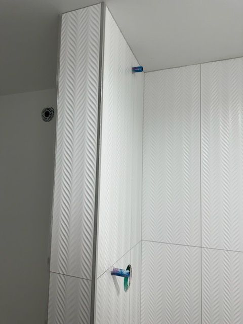 A bathroom with white tiles being installed on the wall.
