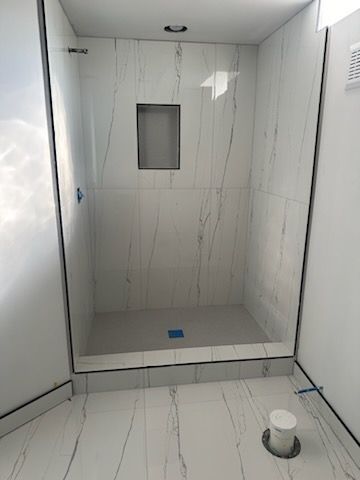 A bathroom with white tiles and a walk in shower.