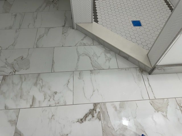 A bathroom floor with white tiles and a blue drain.
