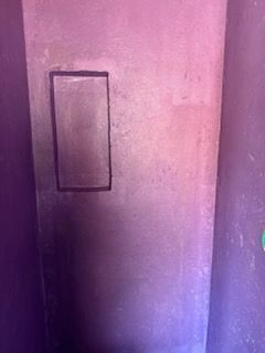 A purple wall with a picture frame on it.