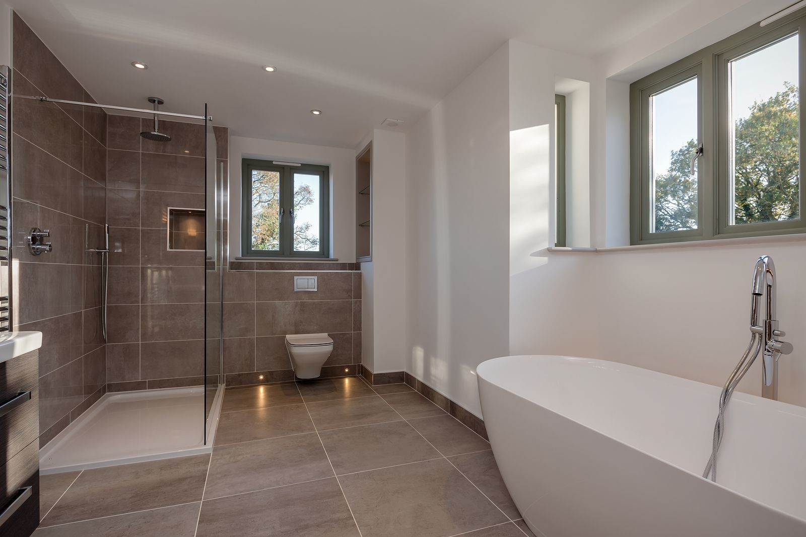 A bathroom with a tub , toilet , shower and window.