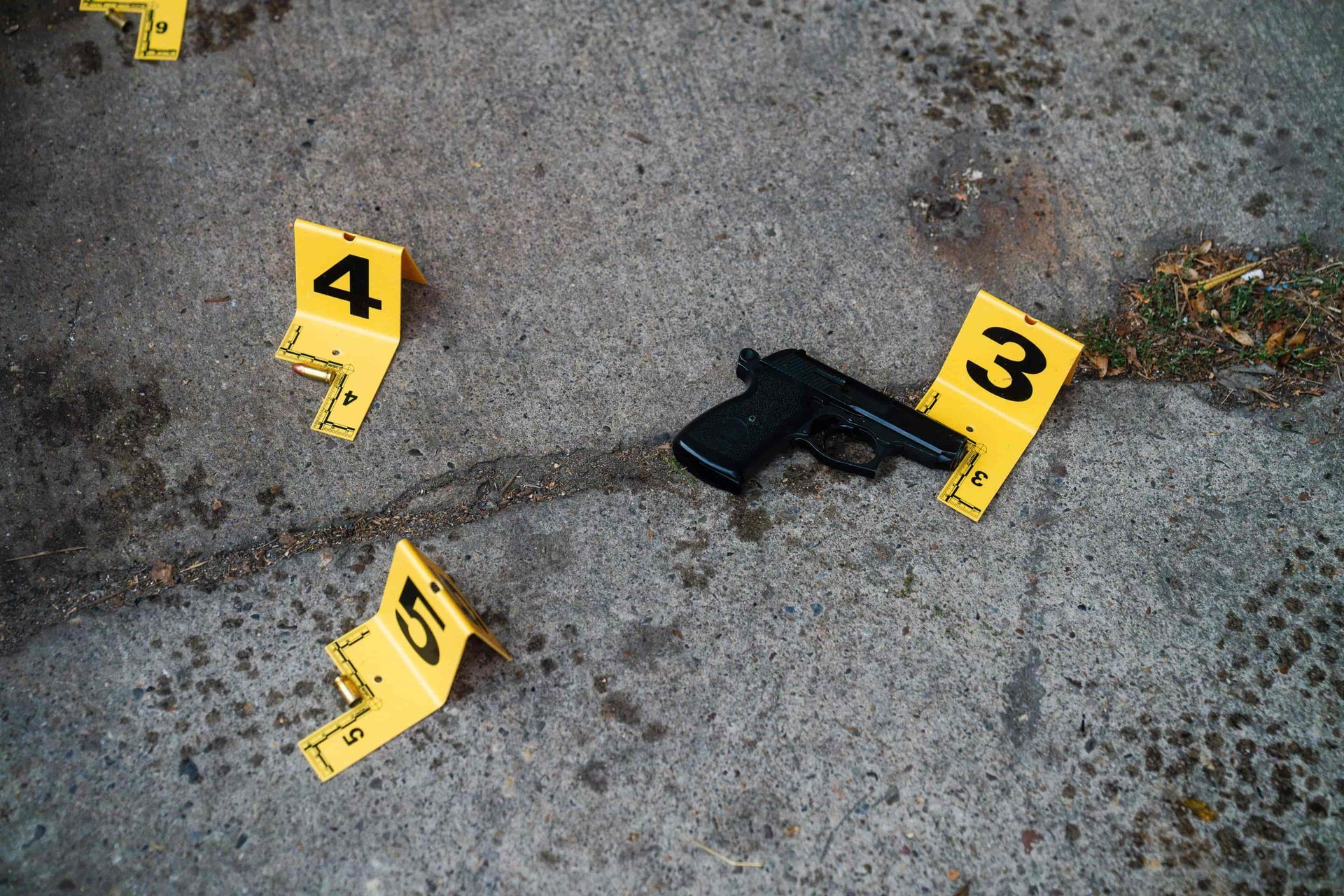 Markierungen für Waffen und Beweismittel an einem Tatort auf Beton.