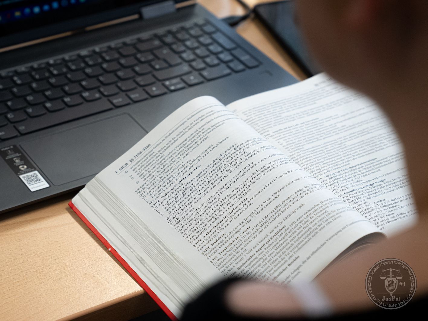Ein Buch wird gelesen, vor einem Laptop.