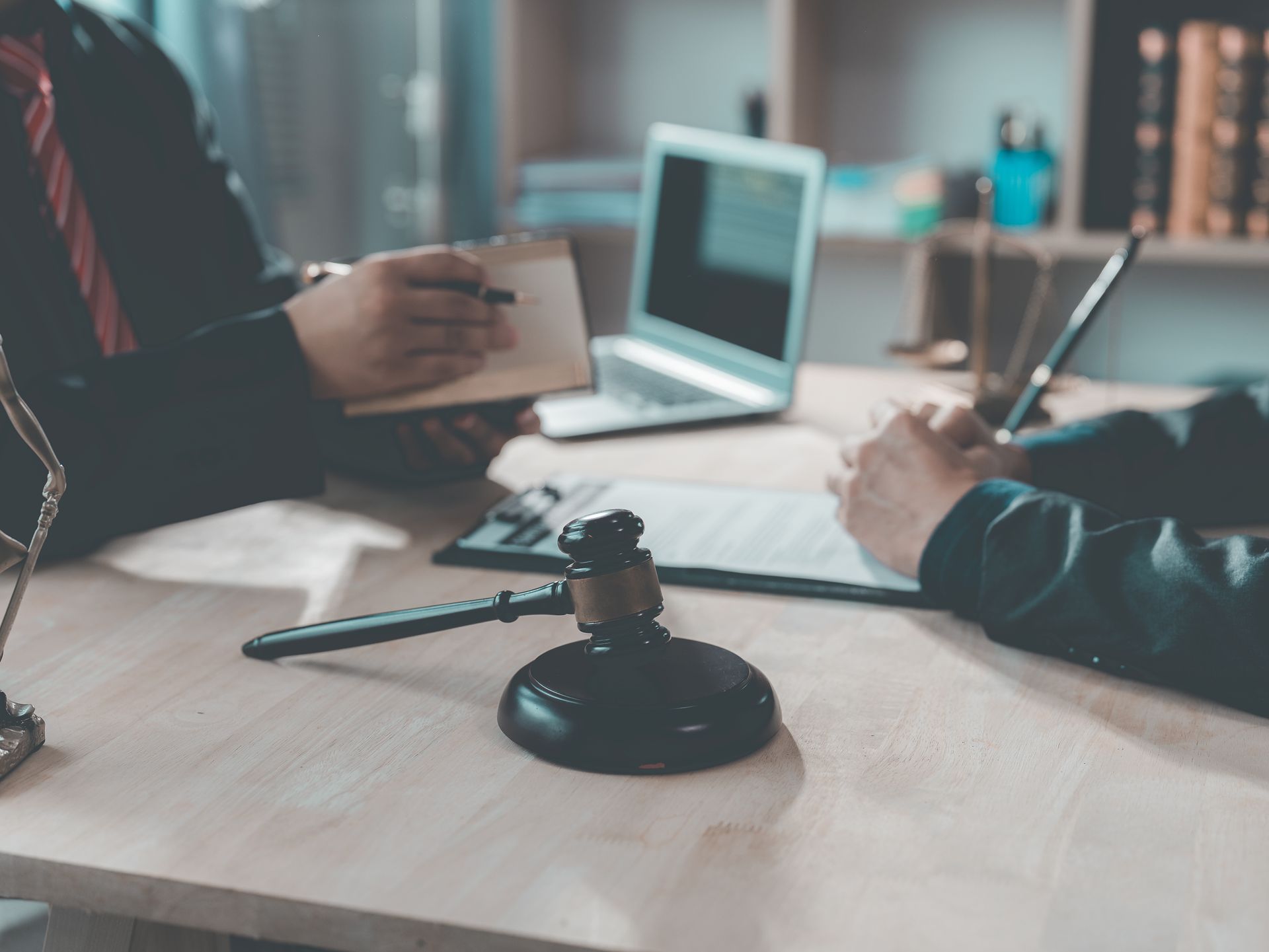 Hands exchanging a document across a desk with a laptop and coffee mug in a meeting room