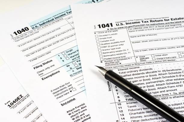 Close-up of three types of tax forms, with a fountain pen on top.