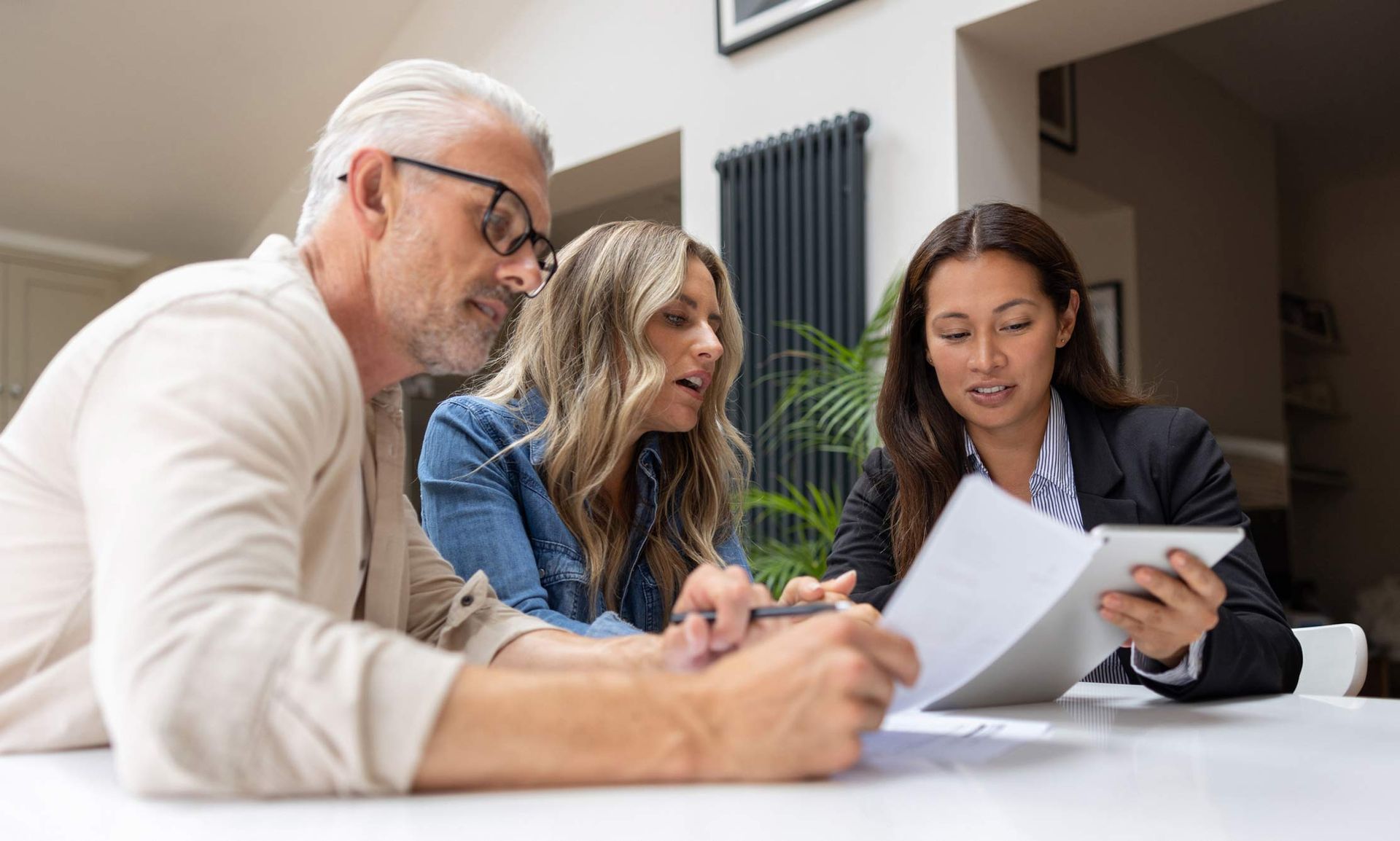 Property tax attorney explaining legal documents to mature couple in modern office setting.