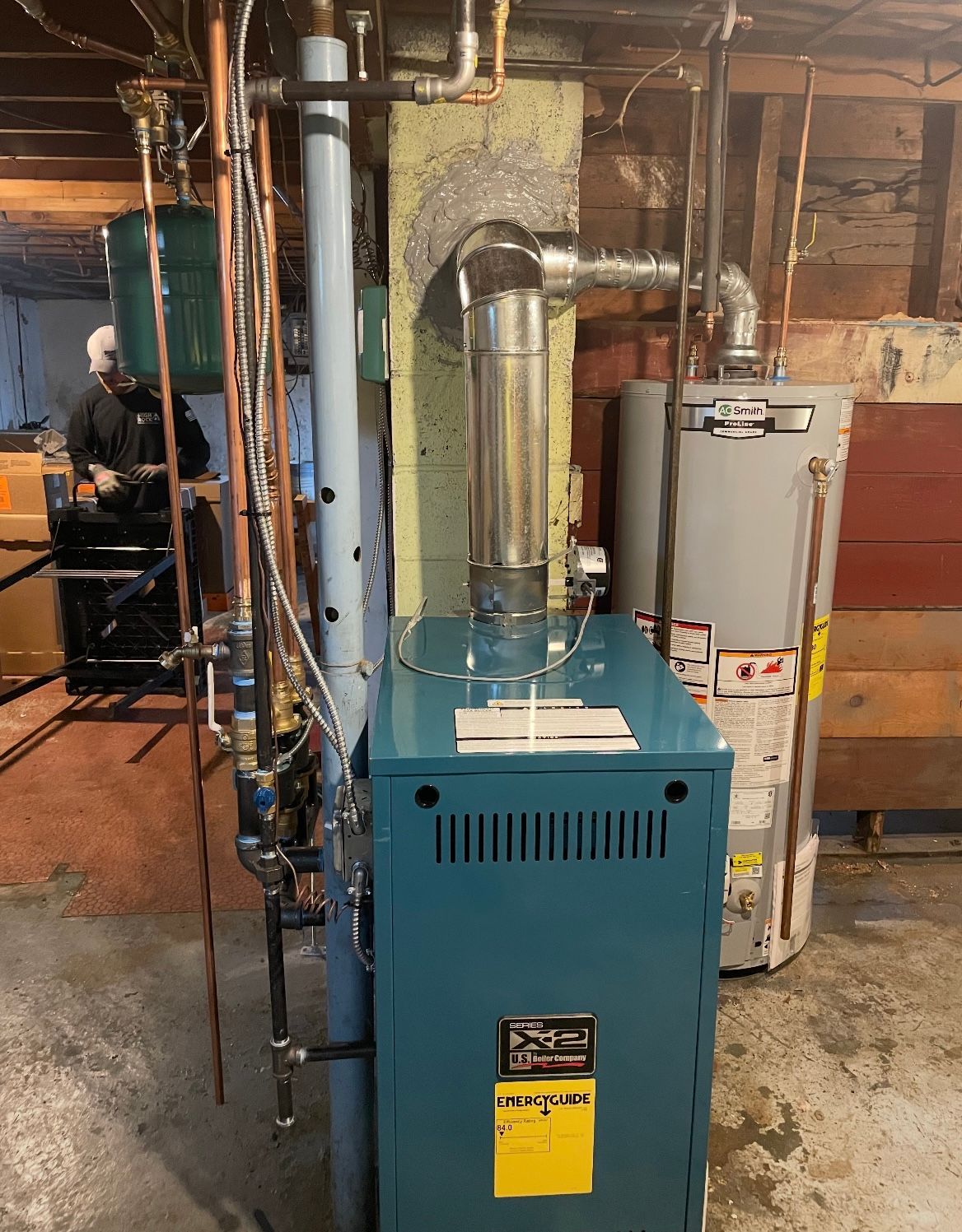 Blue heating boiler with silver exhaust pipe in a basement.