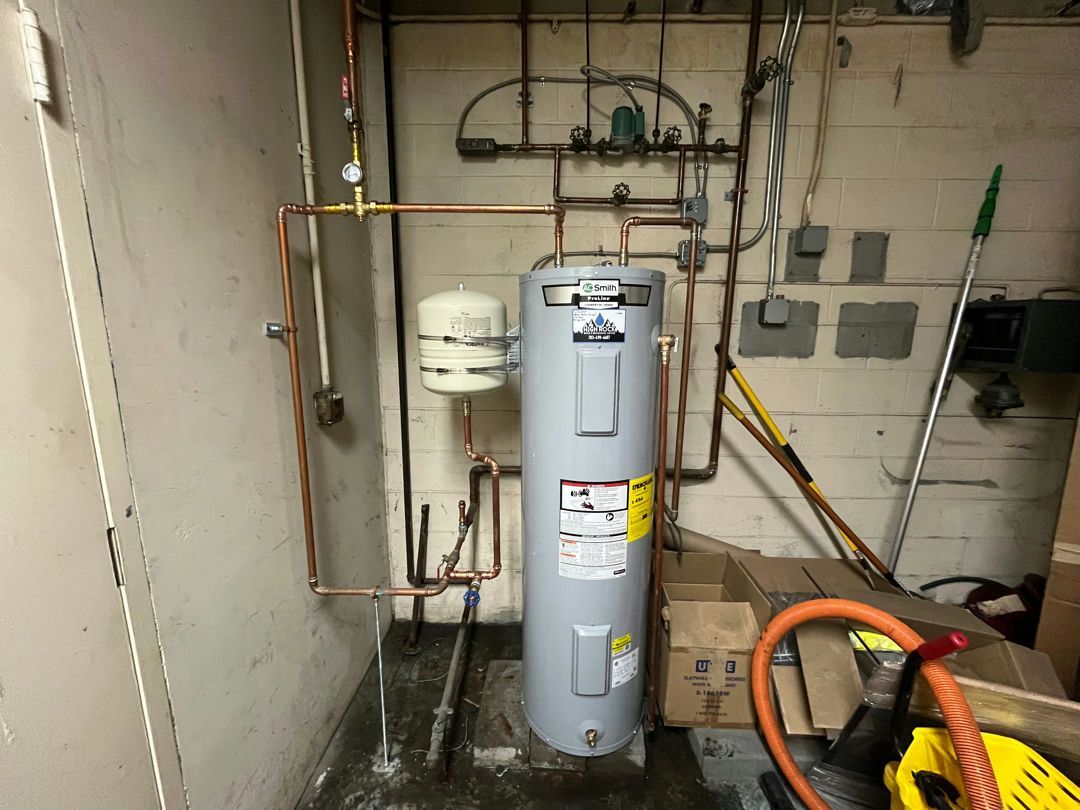 Water heater in a utility room with copper pipes, a white expansion tank, and electrical outlets.
