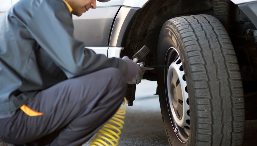 Person Inflating a Tire With Air Hose Near a Vehicle — Elite Fleet Auto in Cannonvale, QLD