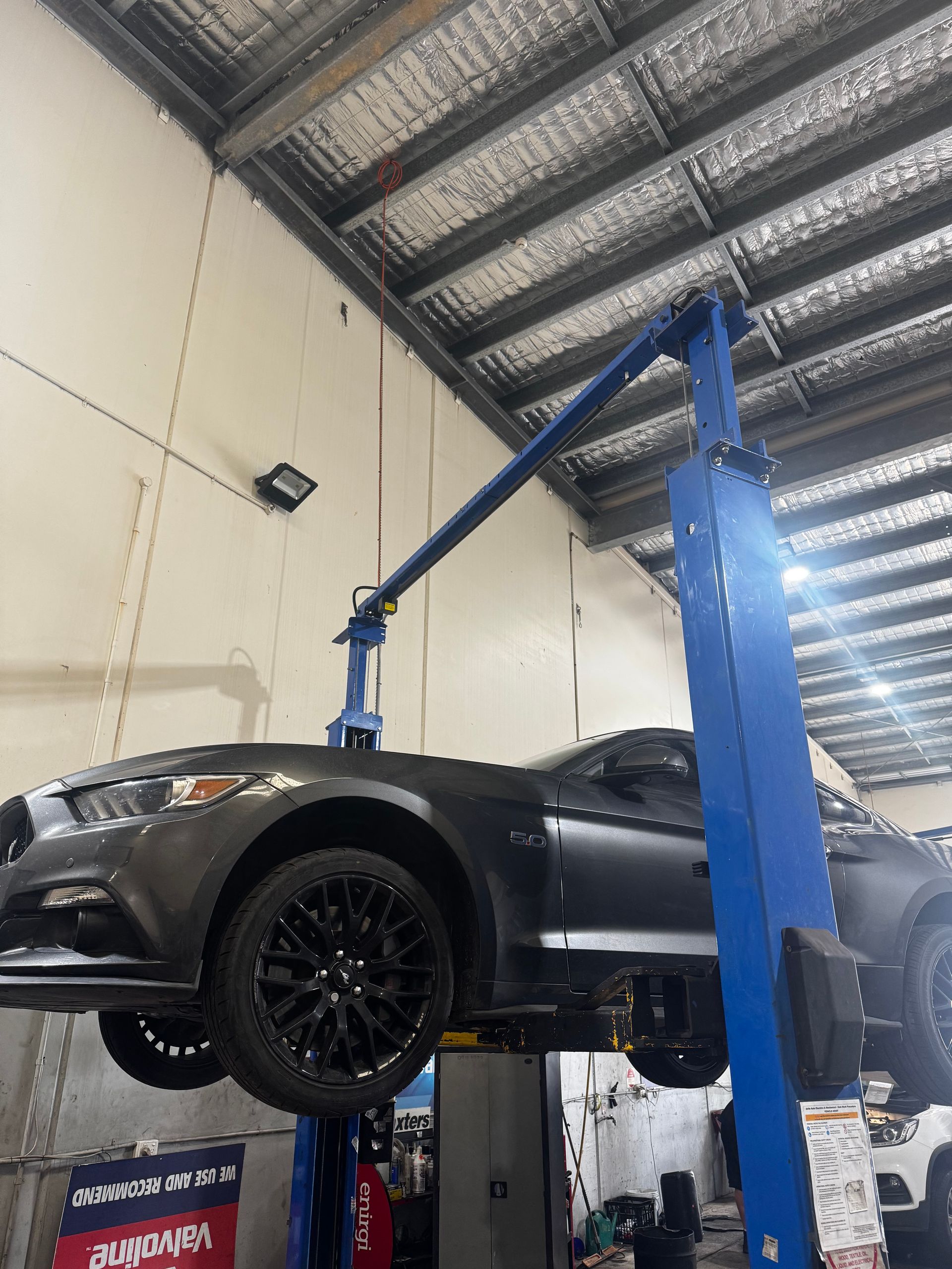 A Dark Gray Ford Mustang Elevated On A Blue — Elite Fleet Auto in Bowen, QLD