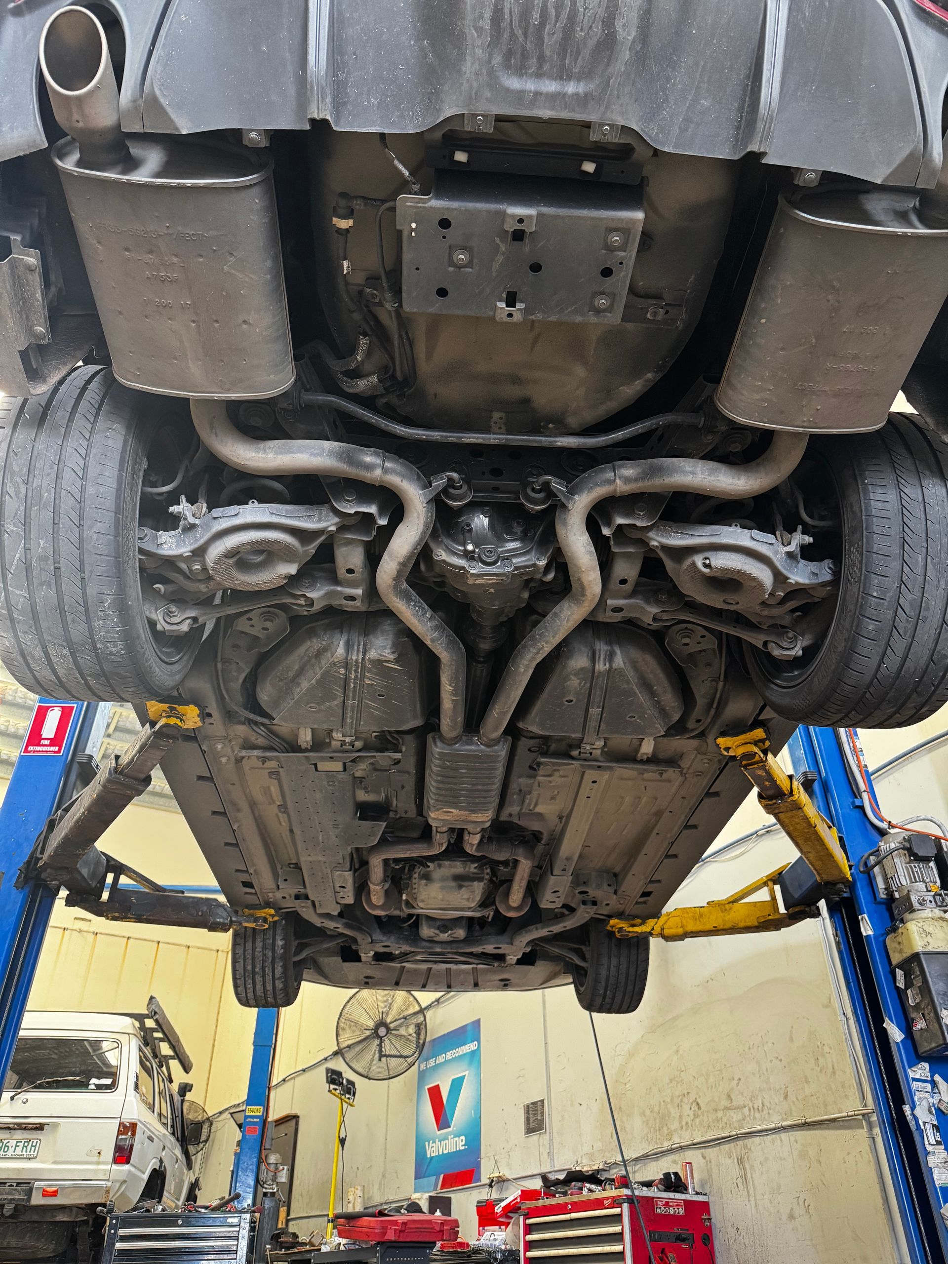 The Undercarriage Of A Vehicle Lifted On A Hydraulic Hoist — Elite Fleet Auto in Cannonvale, QLD