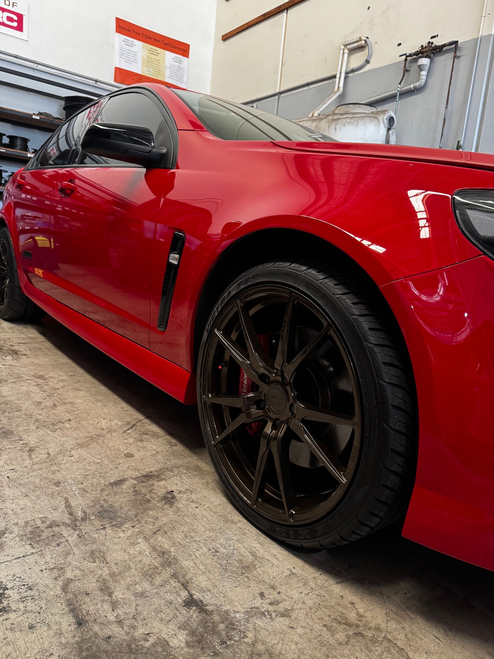 A Low-angle View Of A Shiny Red Sedan With Custom Dark Alloy — Elite Fleet Auto in Cannonvale, QLD