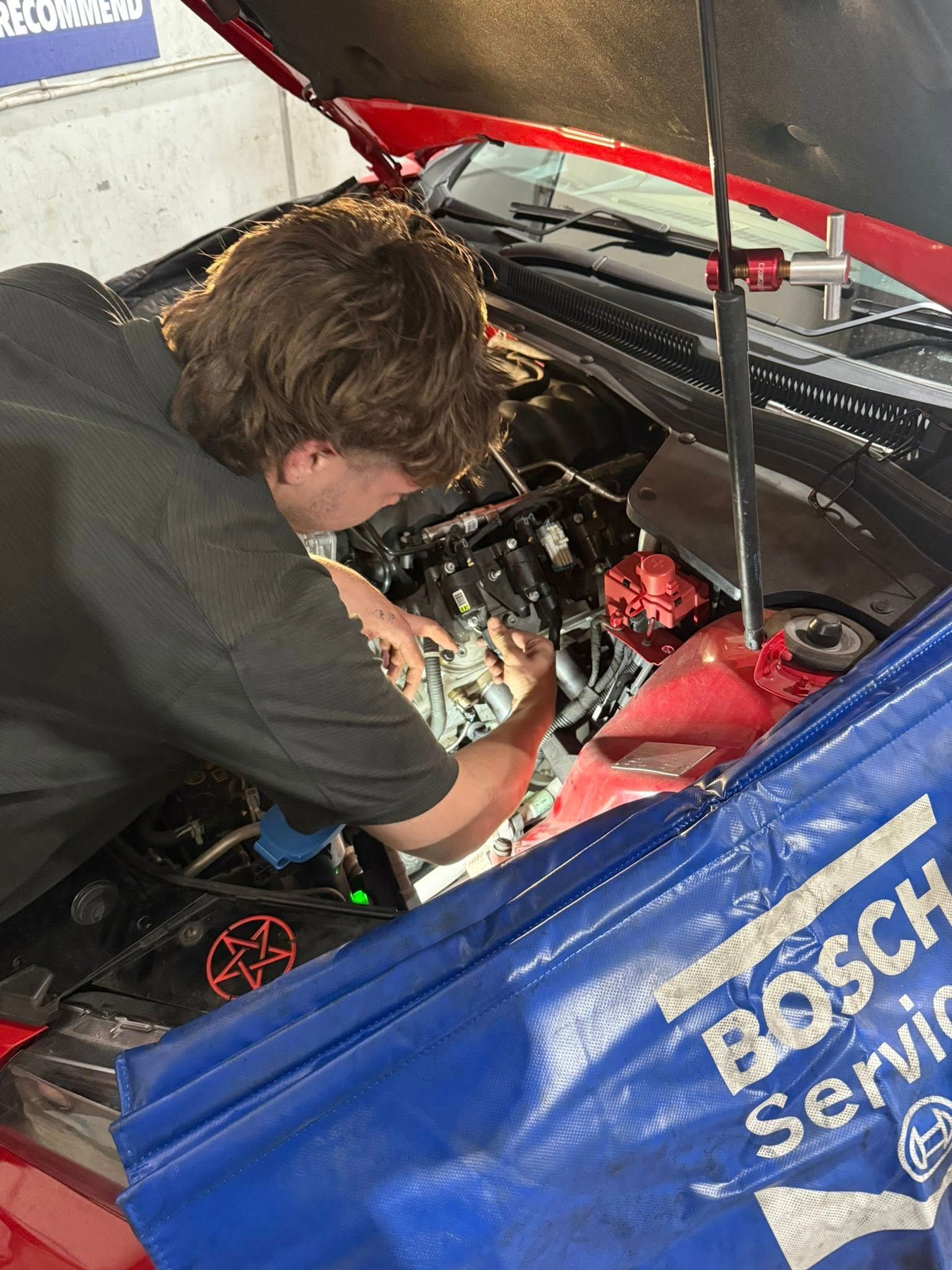 Mechanic Working on a Red Car's Engine Under the Hood in a Garage Setting — Elite Fleet Auto in Cannonvale, QLD
