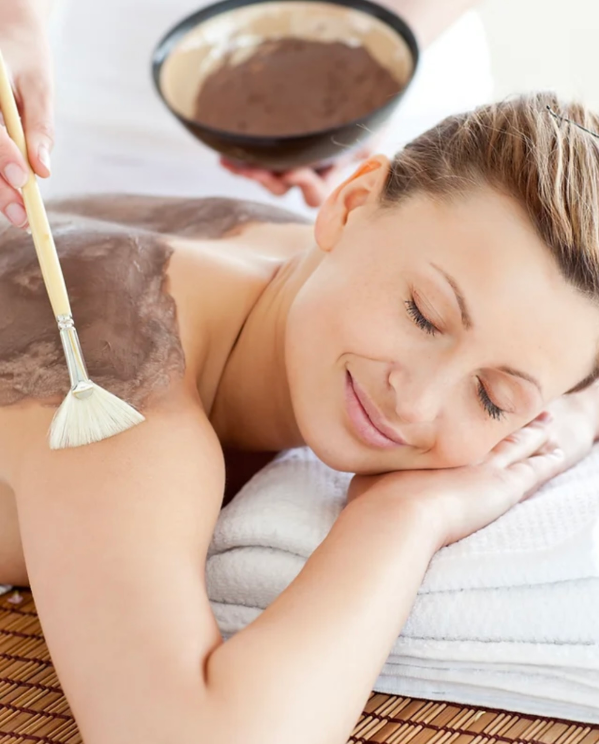 A woman is getting a massage with a bowl of chocolate powder on her back