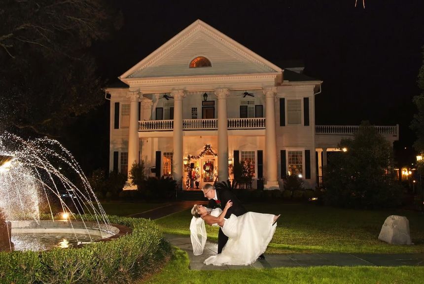 A bride and groom are dancing under a clear tent at their wedding reception.