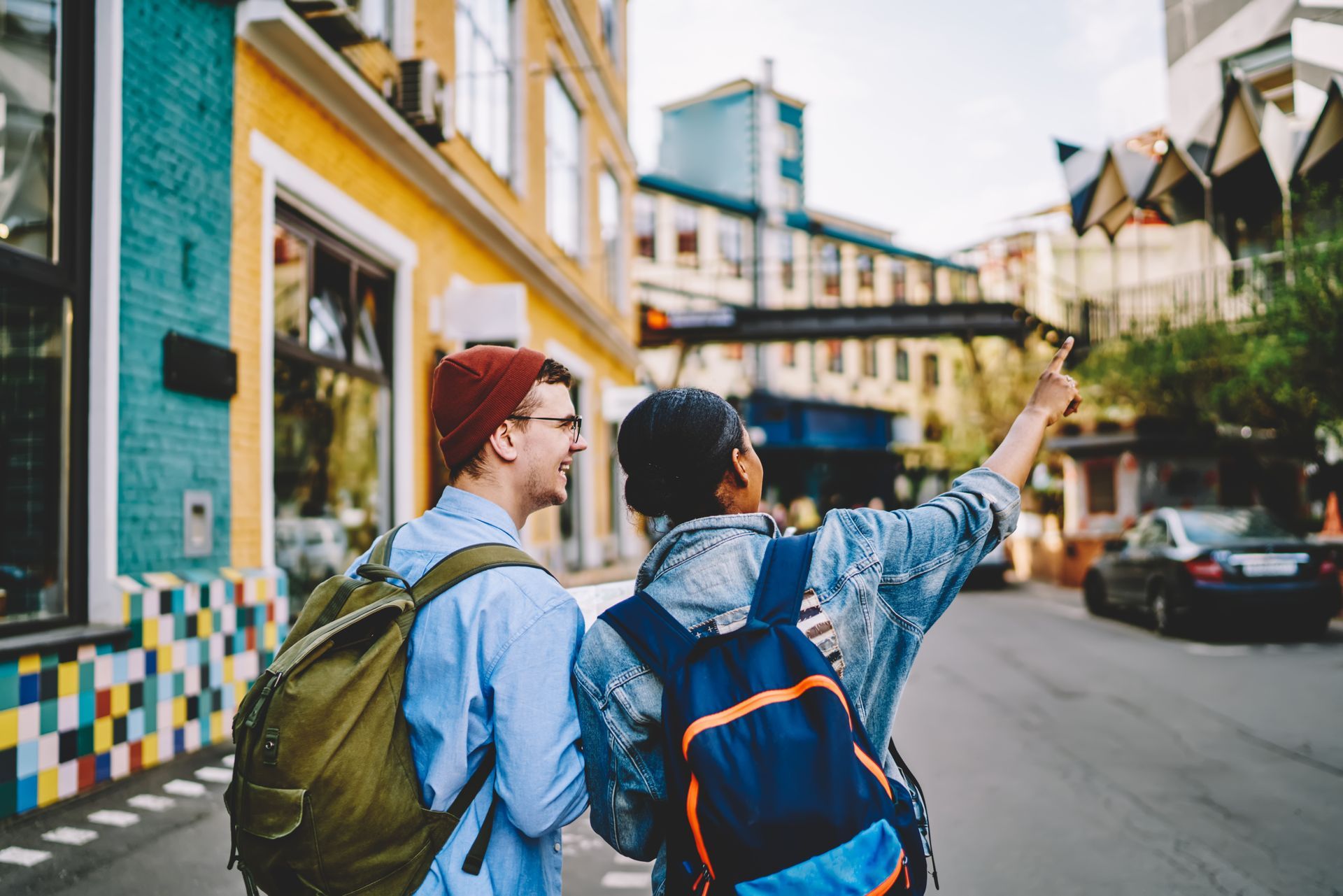 A man and a woman with backpacks are walking down a city street.