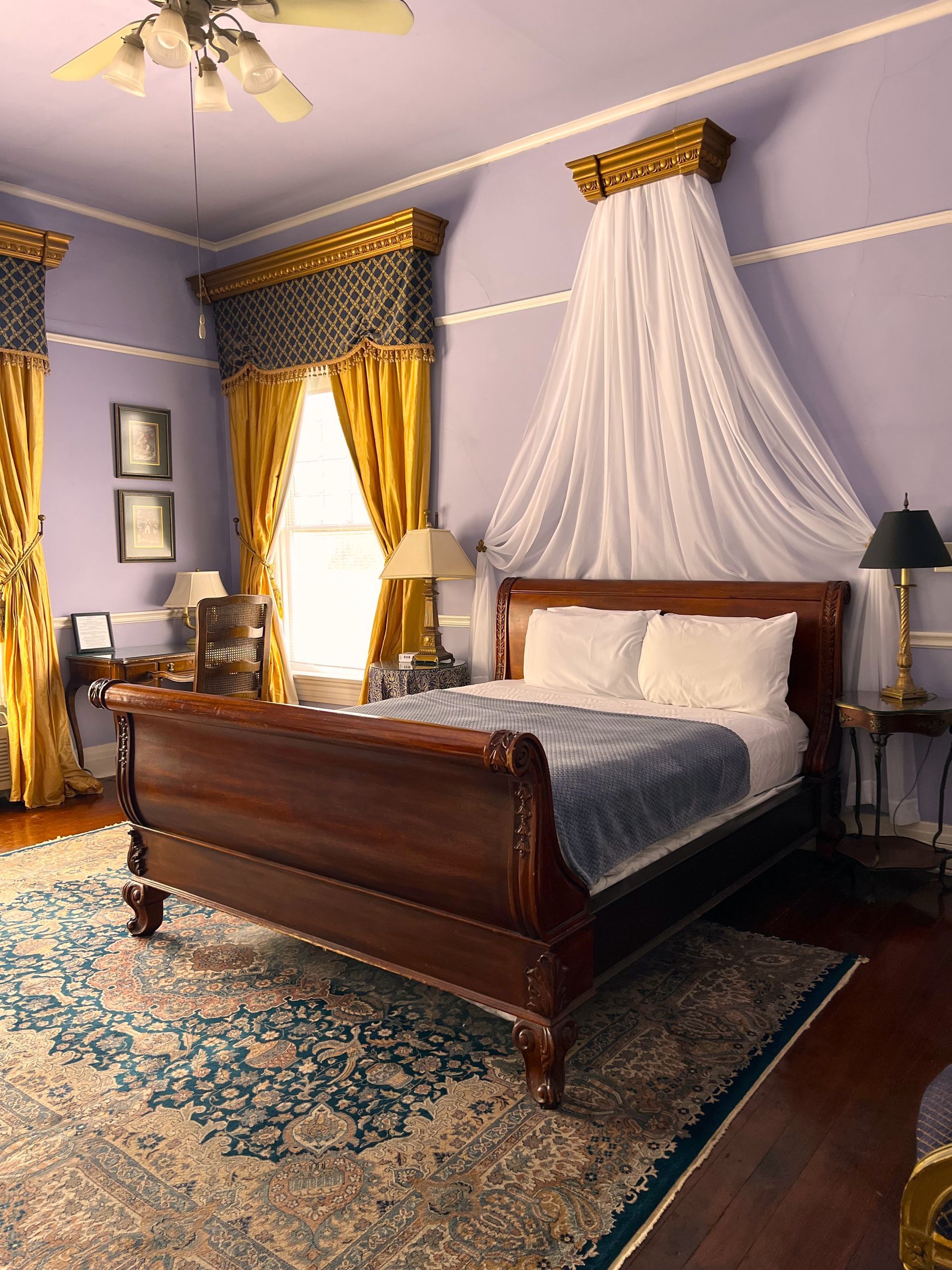 A bedroom with purple walls and a sleigh bed