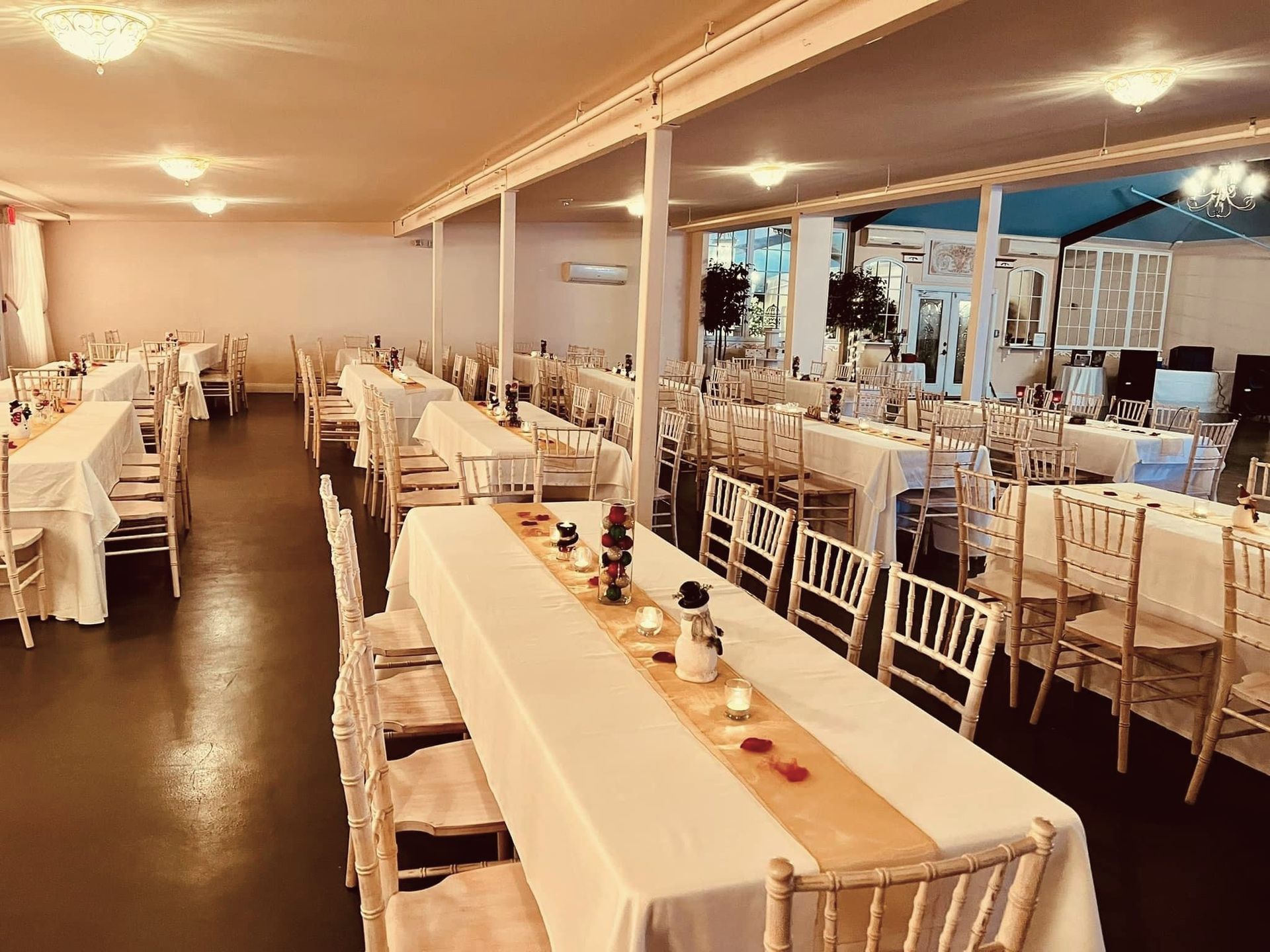 A large room with tables and chairs set up for a wedding reception.