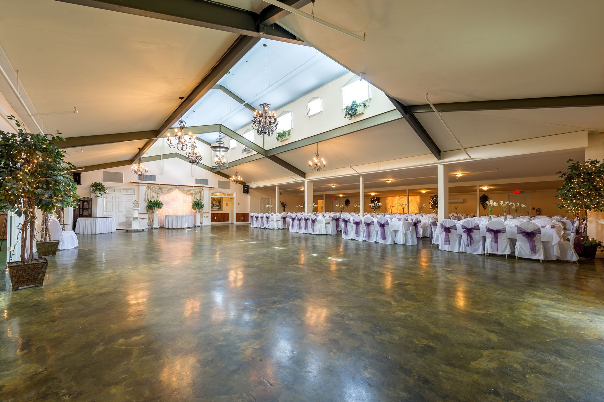 A large empty ballroom with tables and chairs set up for a wedding reception.