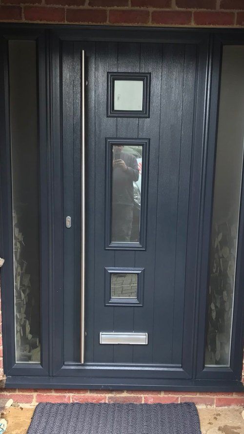A dark blue composite door with long silver handle bar