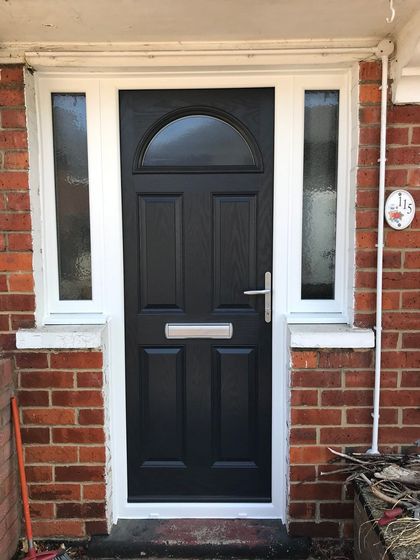 A black composite door surrounded by a white frame