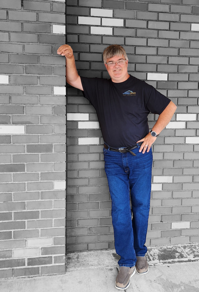 A man is leaning against a brick wall.