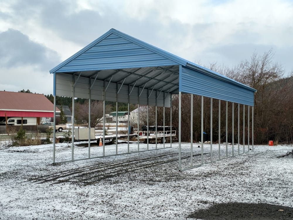 A blue carport is sitting in the middle of a snowy field.